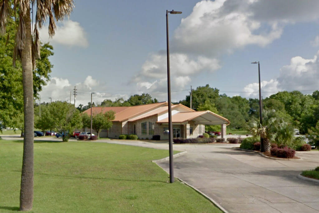 Single story, a-frame brick medical office building with drive-in carport with overhang.