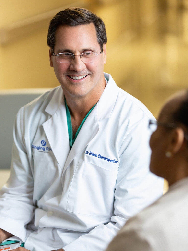 Smiling doctor consults with patient while sitting down